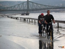 kerékpárosok gázolnak át  a kiöntött Dunán a Szabadság híd felől